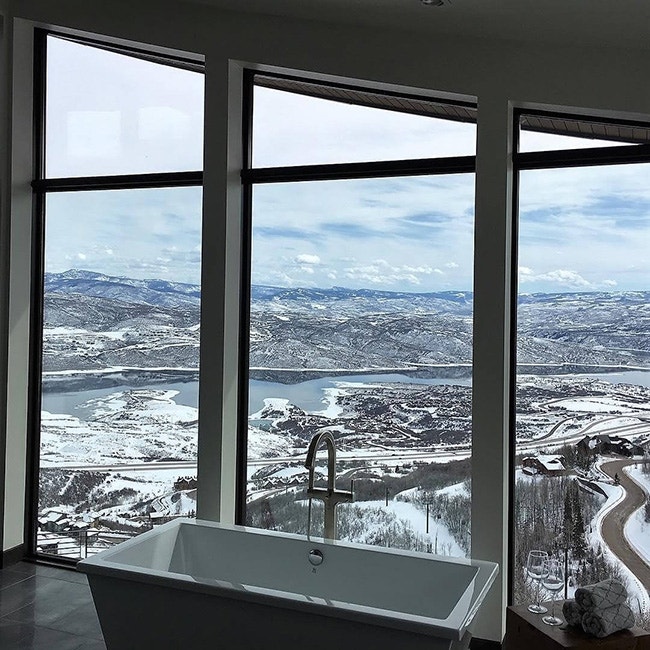 Modern bathroom in Utah with custom window shapes and view of snow-capped mountains