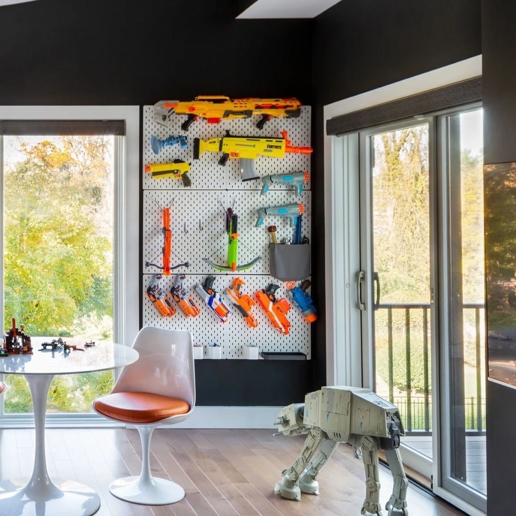 A bright playroom features Nerf guns and other toys with two white sliding patio doors connecting to the backyard.