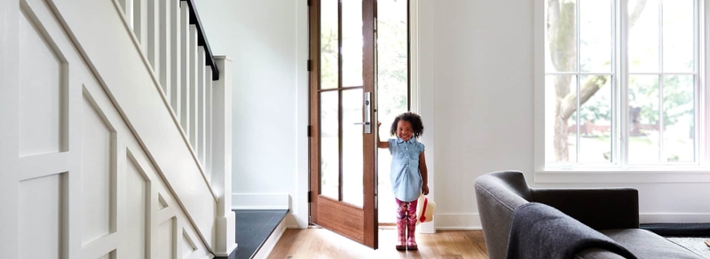 small child walking into a home through a full light entry door