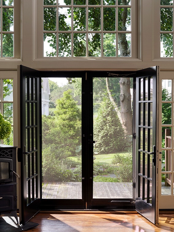 Black sliding doors open to a lush garden view, illustrating stylish sliding door ideas.