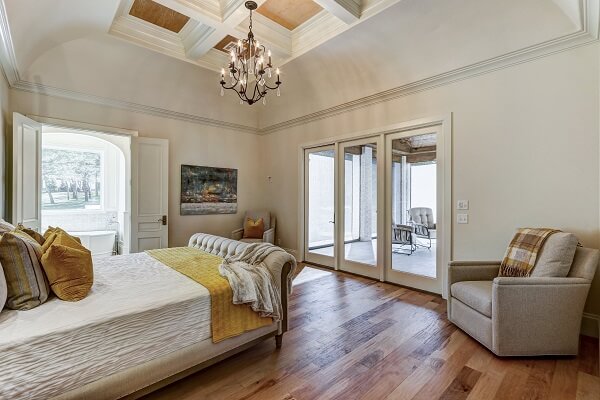 Large bedroom with double doors leading to master bathroom and a hinged patio door leading to patio