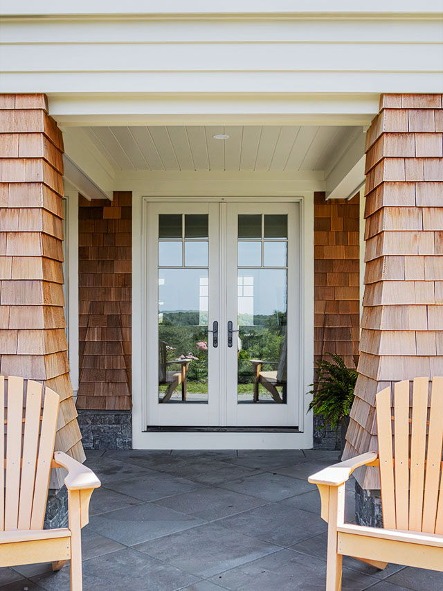 Coastal home front entry with white French doors and cedar shingles.