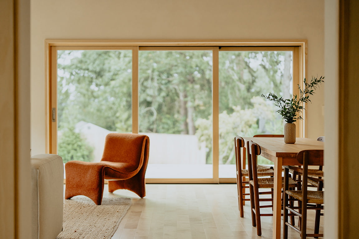 A contemporary orange recliner sits in front of a large wood sliding patio door.