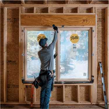 a Pella team member installing a set of Pella windows, viewed from the interior of the new home