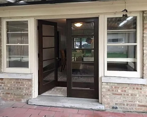 Black french doors flanked by white wood single-hung windows.