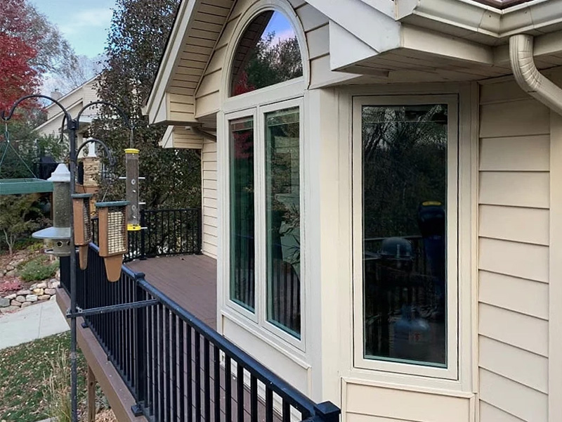 The side view of a home exterior that has tan siding and tan windows.