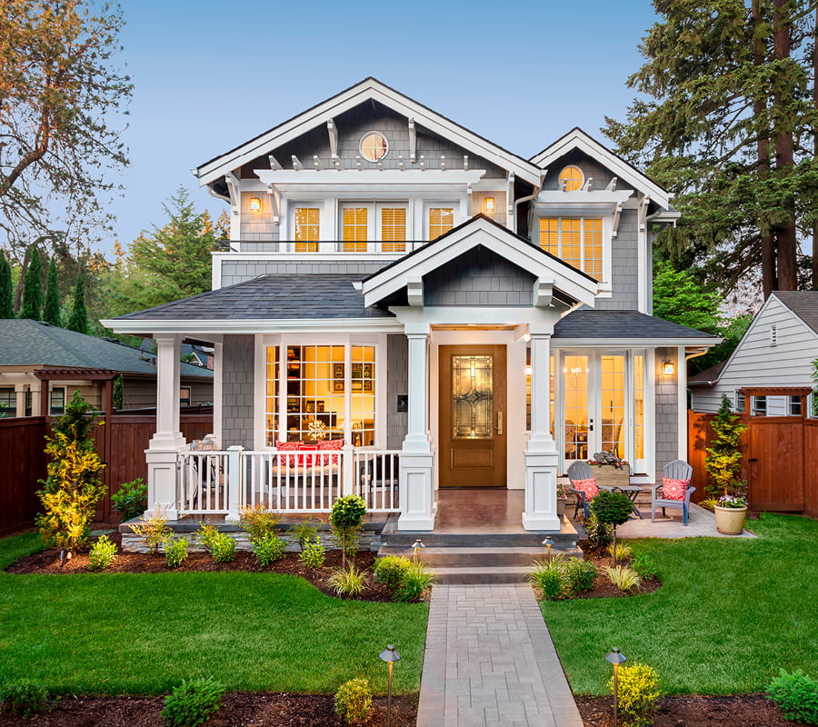 Two Story gray siding home with wood entry door and white framed windows with grilles