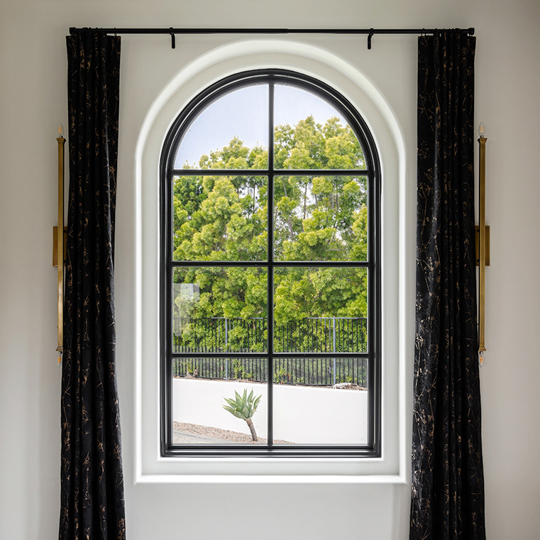 Closeup of arched window with black grilles in Encinitas home.