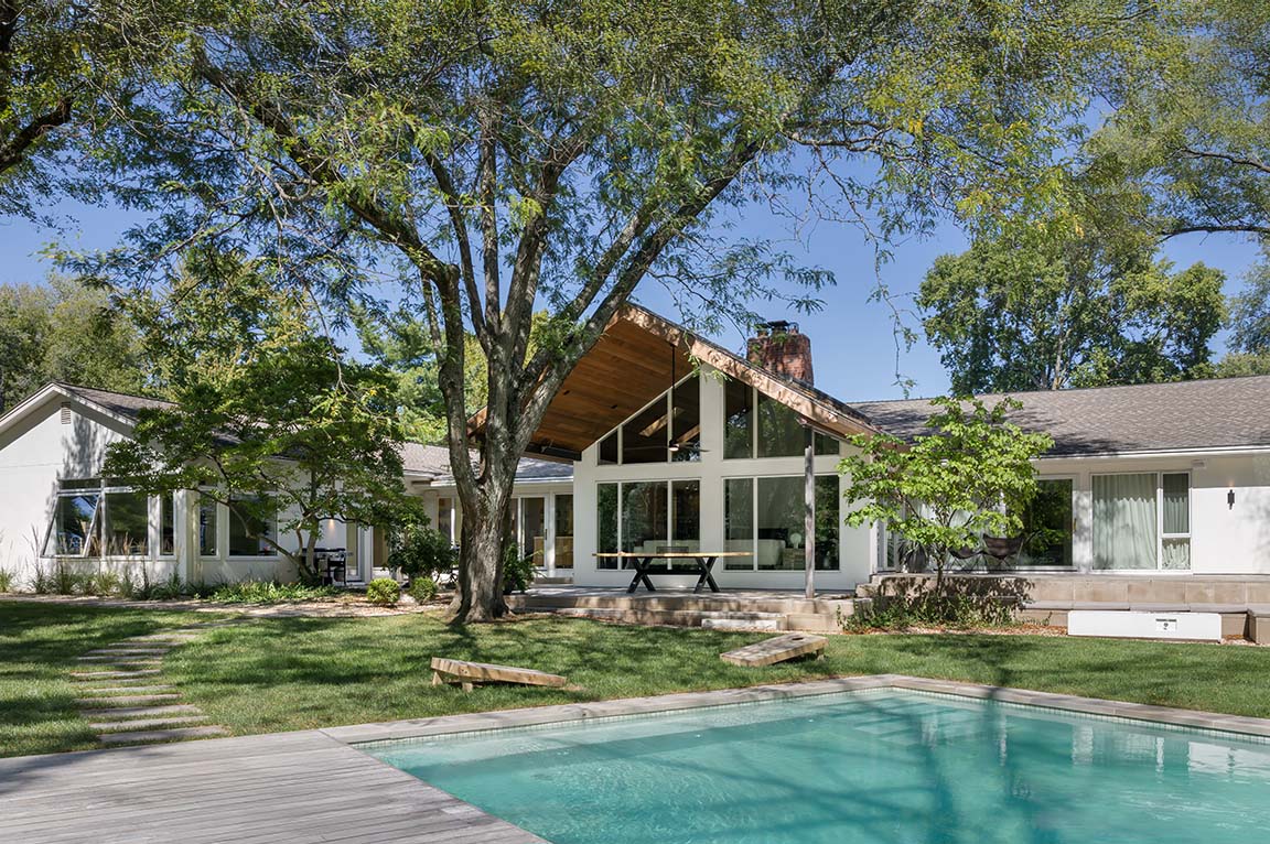 Modern ranch-style home with large windows overlooking a backyard patio and pool.
