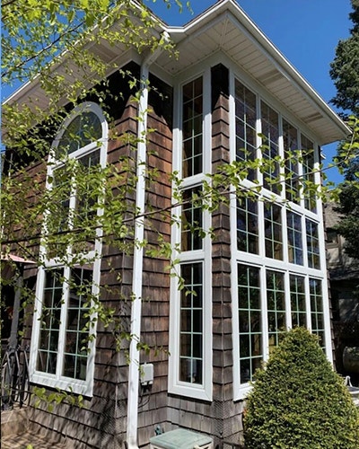 Curbside view of a house with newly installed floor-to-ceiling windows.