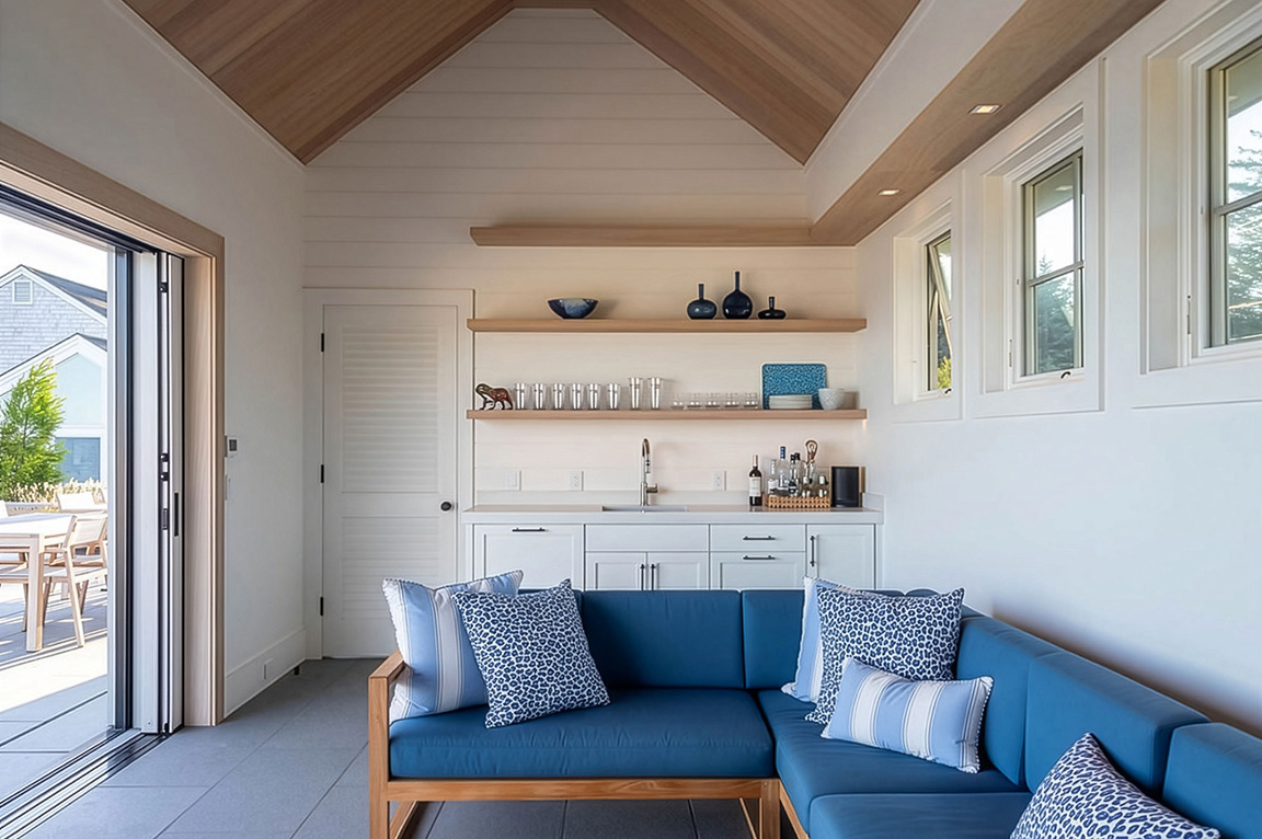 Modern pool house interior with blue sectional sofa, wood ceiling, and open shelves