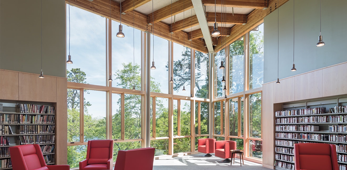 library with red chairs and a window-filled corner floor to ceiling