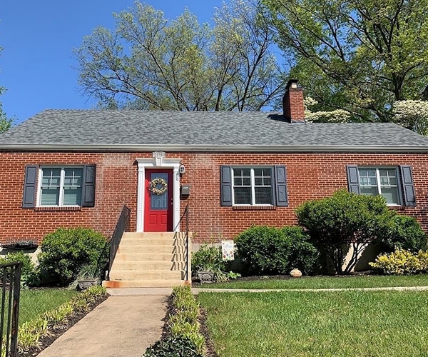 A brick, cape cod-style home with new windows and black shutters