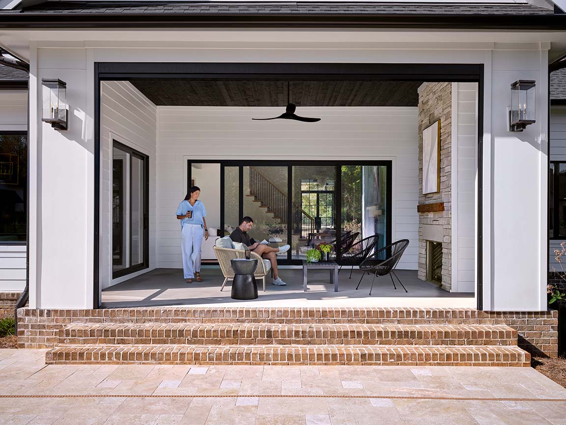 Black multi-slide patio door that opens to a covered patio that also includes an outdoor fireplace.