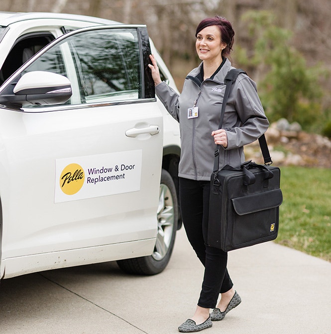 A Pella replacement service vehicle with a representative holding a bag.