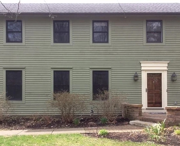 Curbside view of colonial style home with outdated windows.