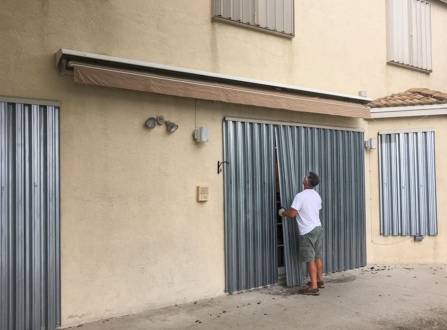 hurricane shutters being placed over both windows and doors