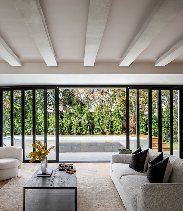 6-panel multi-slide patio door opens a contemporary living room to an outdoor patio surrounded by greenery.