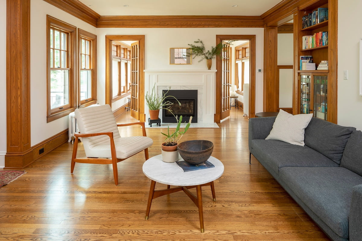 A cozy living room space with a couch and chair features wood floors and craftsman windows.