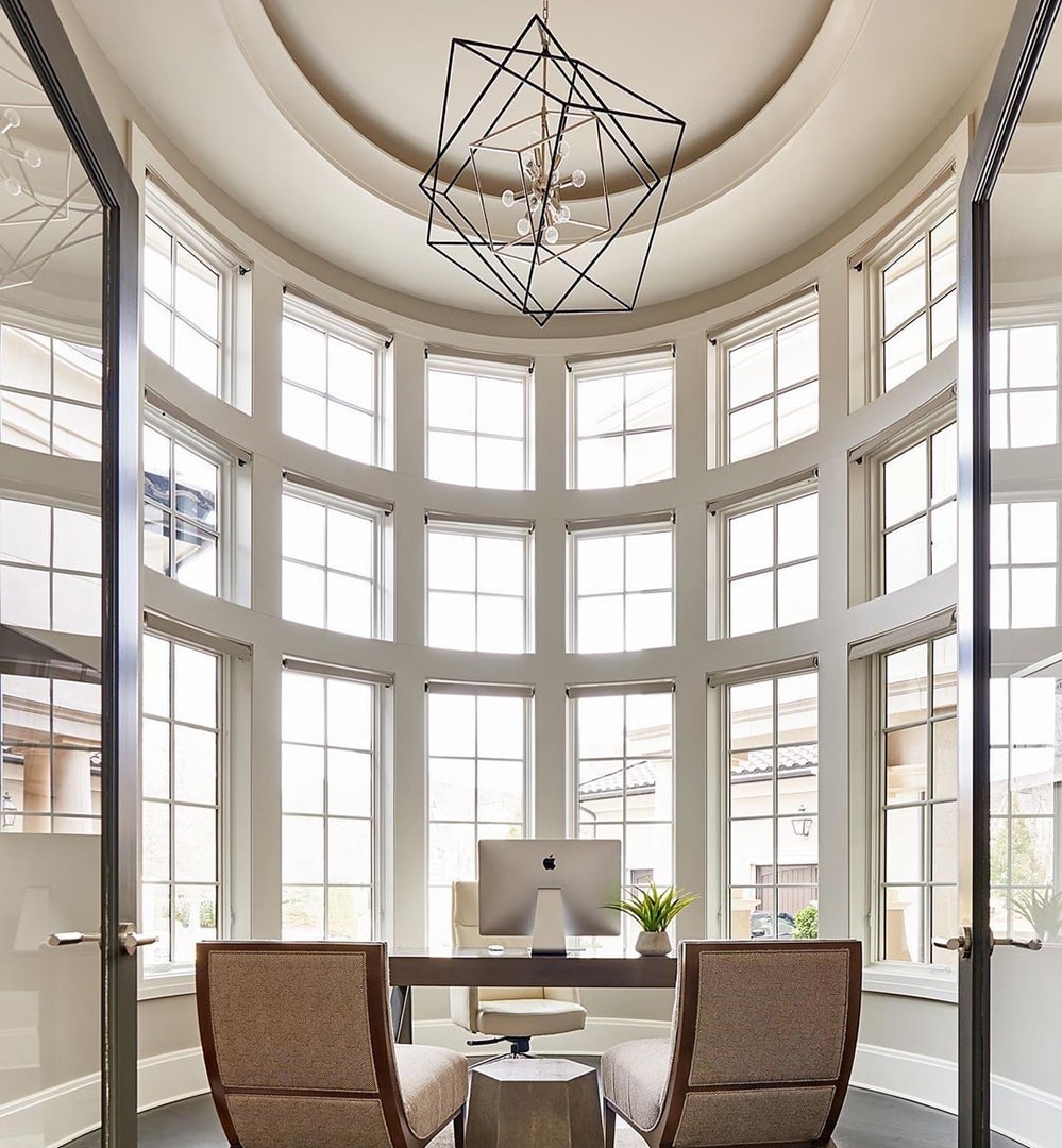 Office with curved walls features a mixture of casement and picture windows from the floor to the ceiling.
