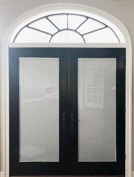Interior view of newly installed black Pella patio doors allowing for natural light and privacy.