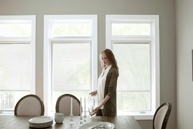 red-headed woman setting a table with three lifestyle series windows behind her