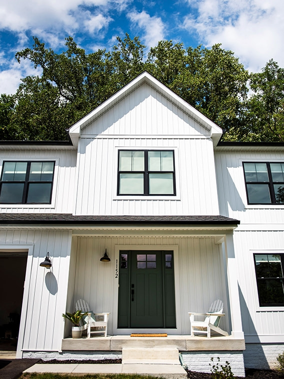 A white farmhouse exterior featuring black farmhouse windows and a green front door.