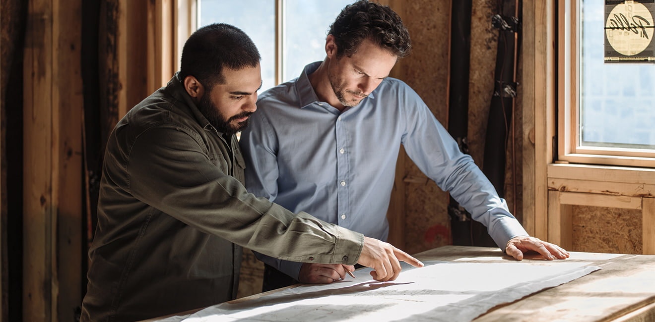 two professionals discussing blueprints in a home under construction