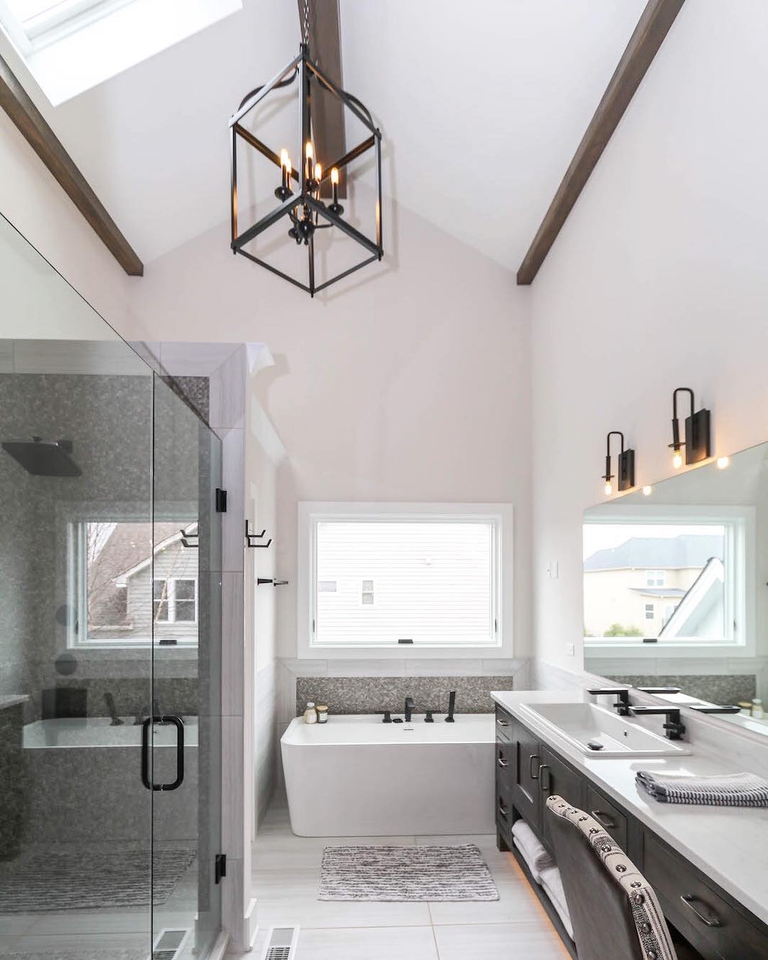 modern bathroom with glass shower and awning window over freestanding tub