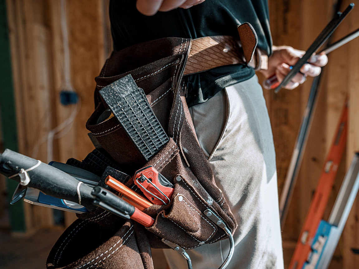 A large leather tool belt is full of various construction tool.