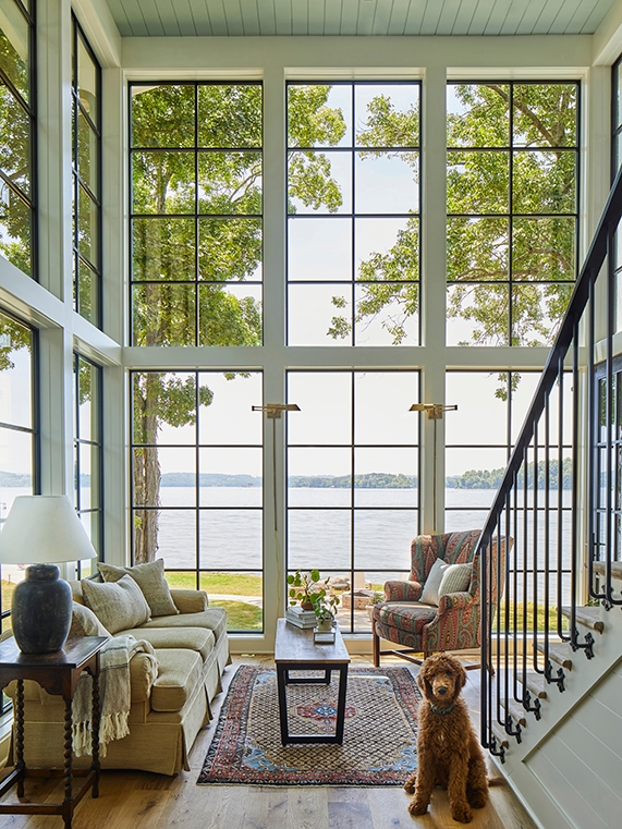 Interior view of living room with two stories of floor-to-ceiling black windows. 