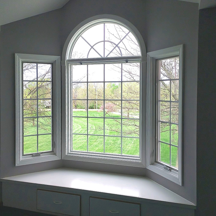 A bay window with energy efficient windows, showcasing a view of the green landscape outside.