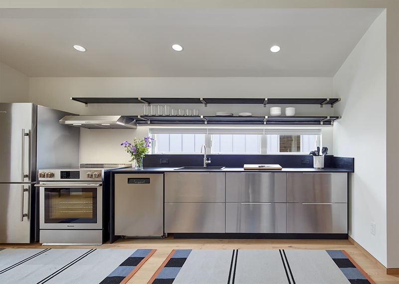 Industrial style kitchen with stainless steel appliances and cabinets with a long rectangle window above the counter top