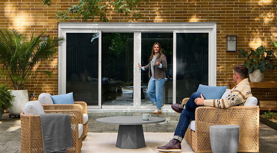 White sliding patio door opening to a modern outdoor seating area with woven furniture.
