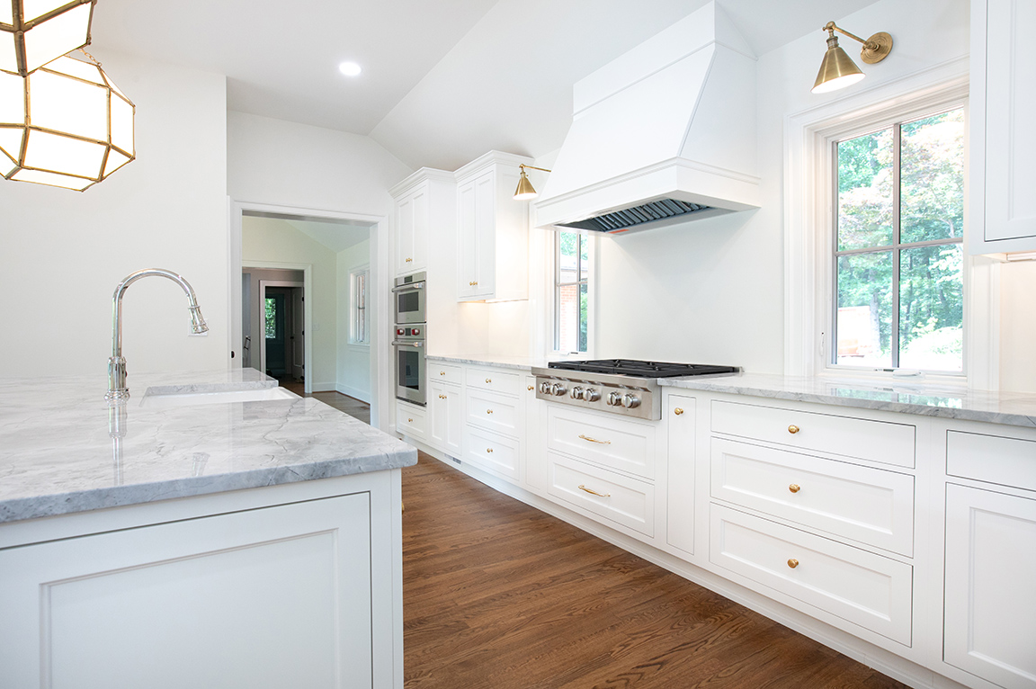 White kitchen with windows flanking each side of stove and hood in Charlottesville new build.