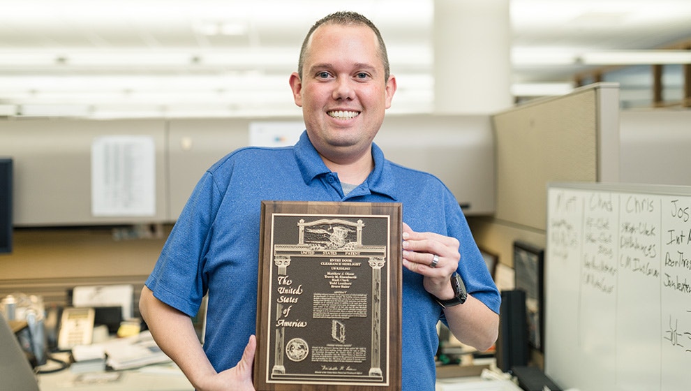 engineer standing with a patent plaque