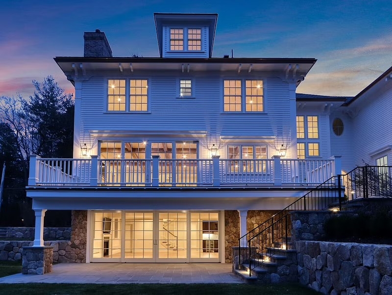 French sliding patio doors on the back of a Boston-area home at dusk, interior light shining through the glass.