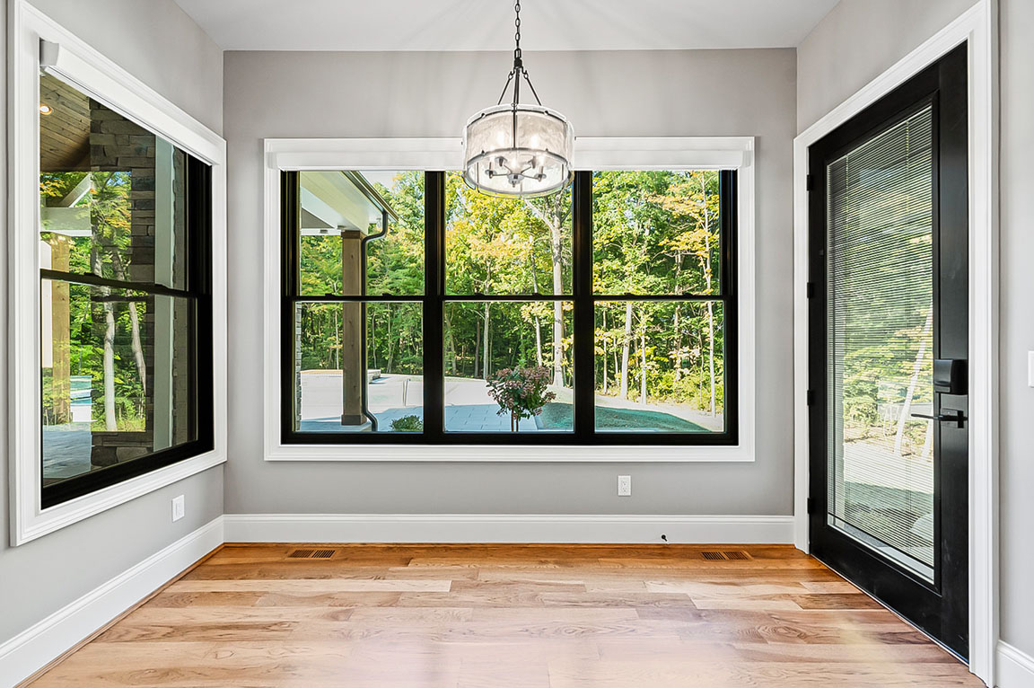 Dining area with large black-trim windows, modern chandelier, and natural light overlooking outdoor view