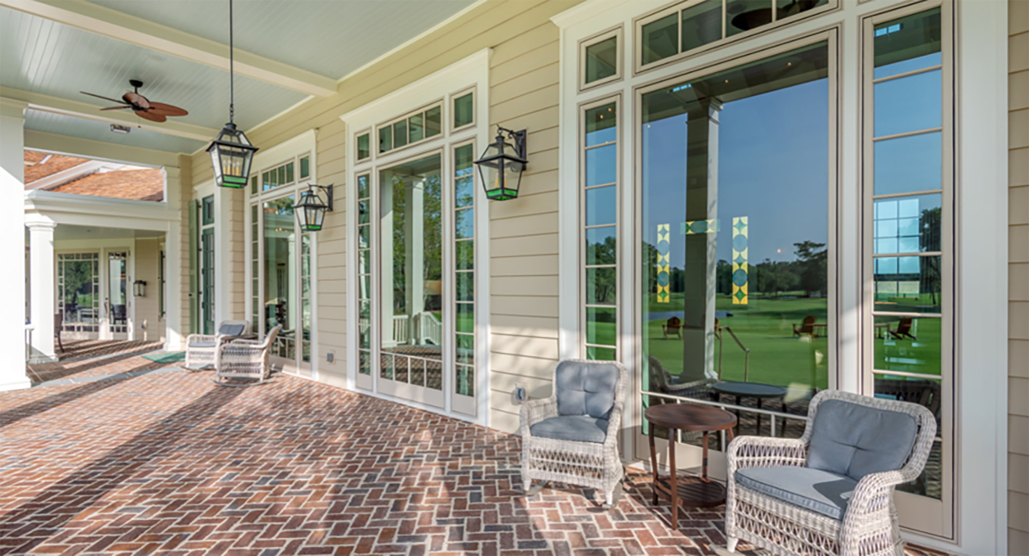 A brick front porch with large tan custom windows on the building's exterior.