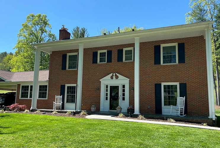 brick home on a sunny day with white windows and a black front entry door