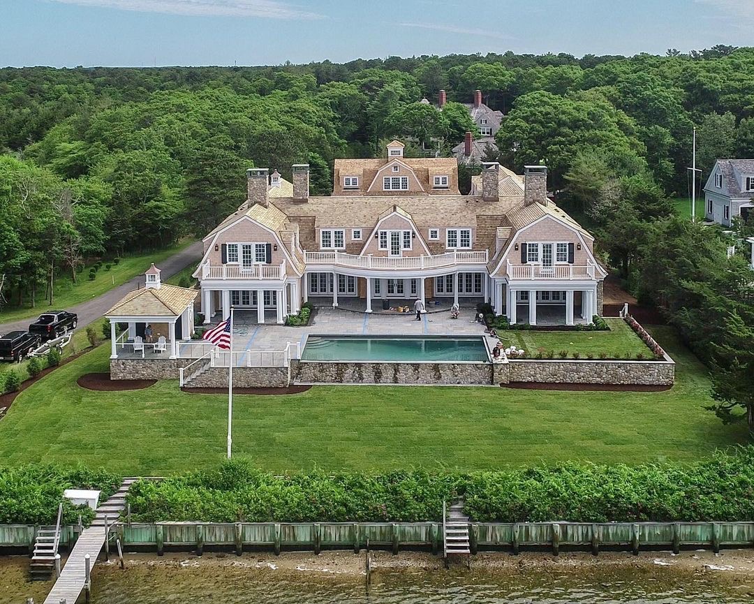 The exterior of a large tan home with white traditional windows and patio doors.