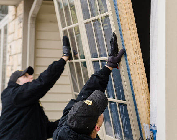 Two Pella contractors are replacing a window unit on an existing home