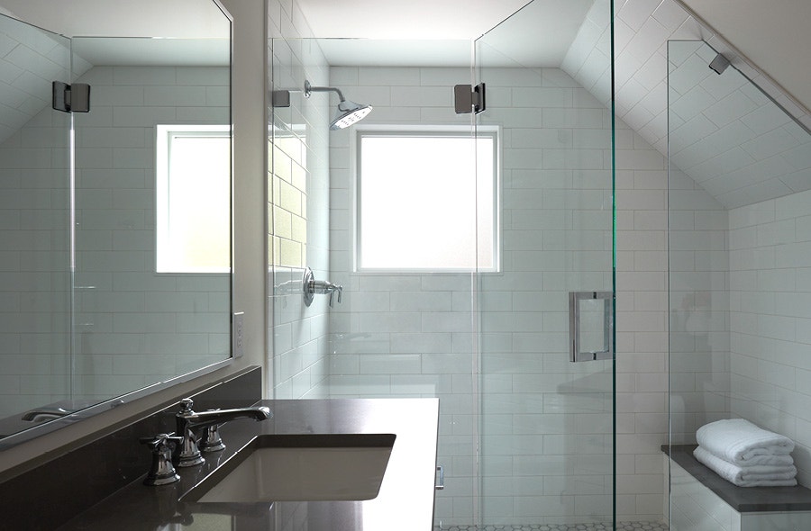 Sleek bathroom with walk in shower and a high window against white tiles