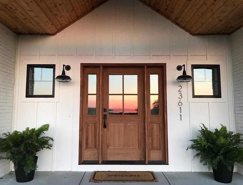 Glass panel on natural wood front door reflects sunset