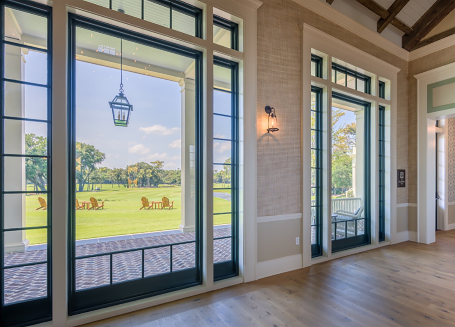 A open space interior features large black picture windows with simple grille patterns.