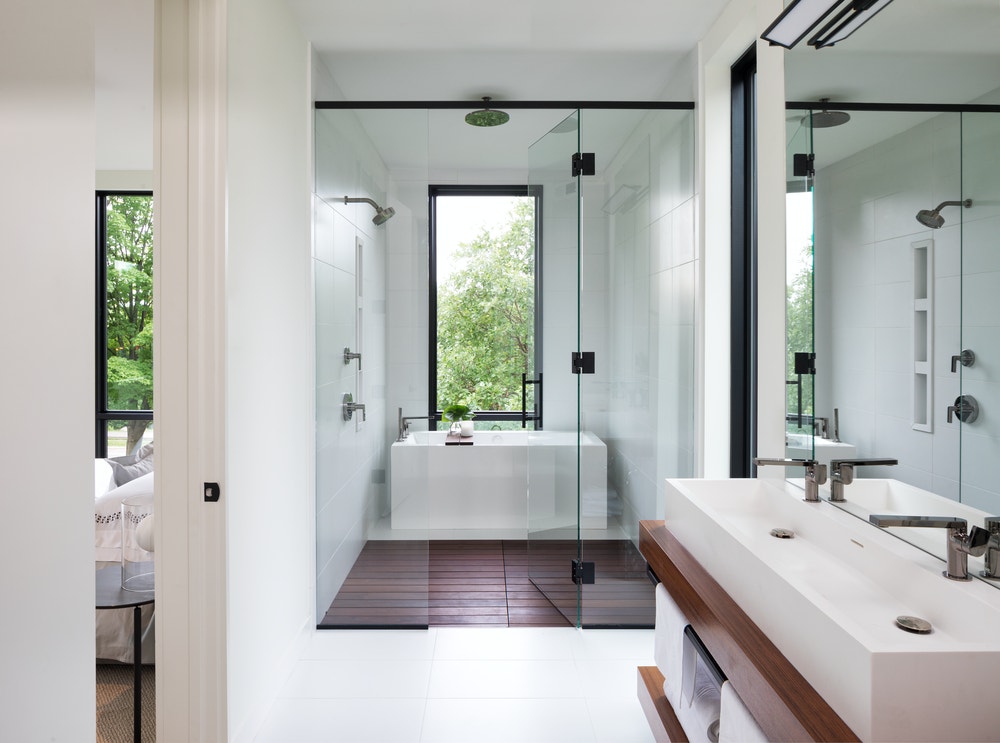 Long bathroom with a separate room for the bathtub with a large black window overhead