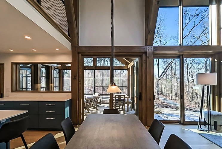 long dining room table in front of a wall of floor-to-ceiling wood windows