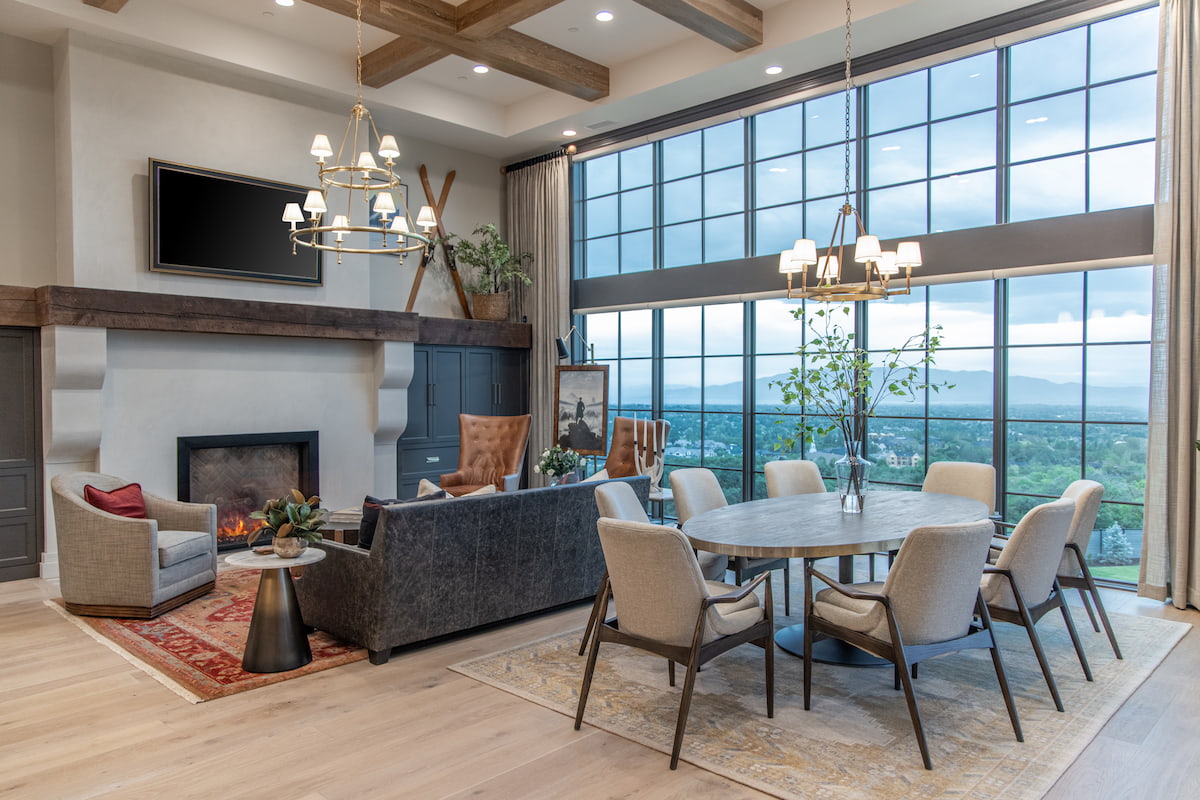 A Utah living room and dining room features gray floor-to-ceiling windows as the backdrop.