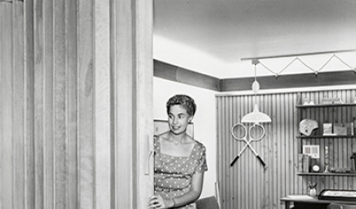 In the 1950s Pella released the wood folding door, as seen in this historical image of a woman operating the door.