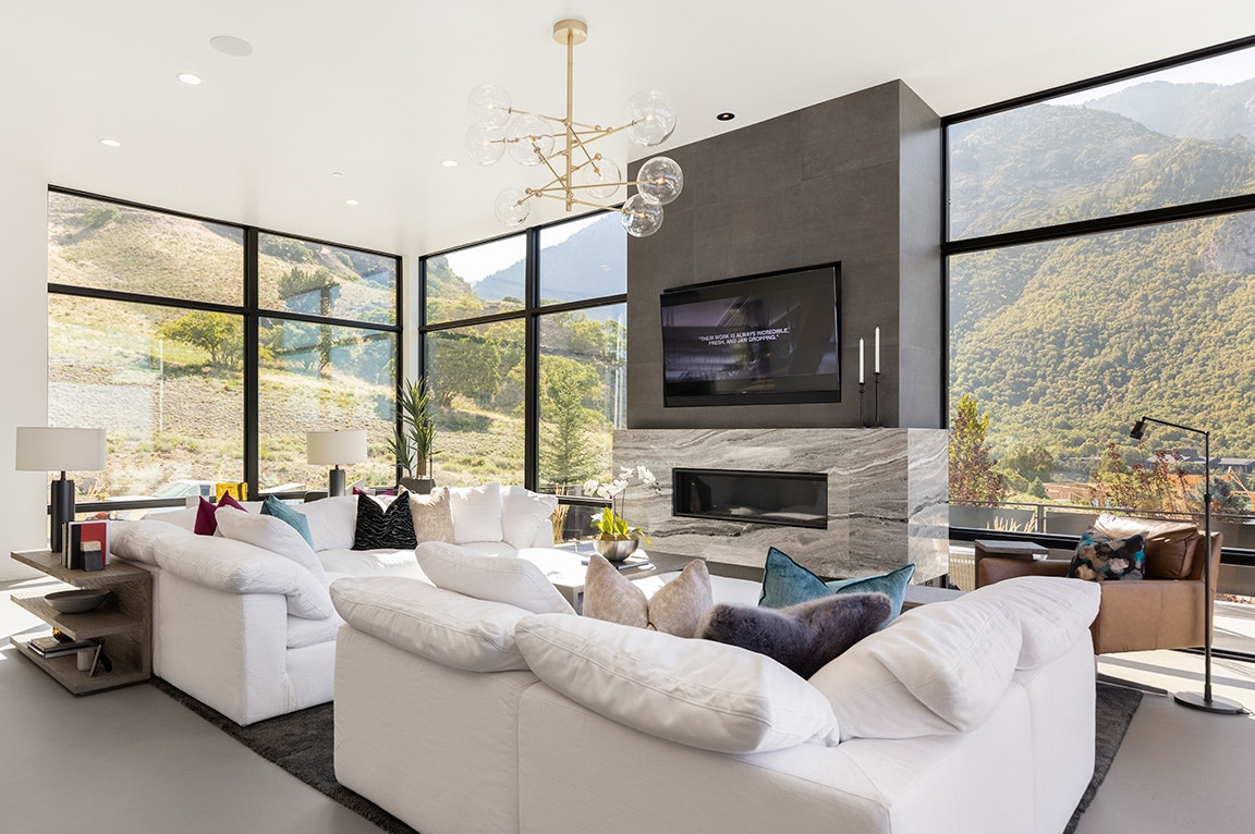 Spacious modern living room with floor-to-ceiling windows showcasing a scenic mountain view and white sofas.